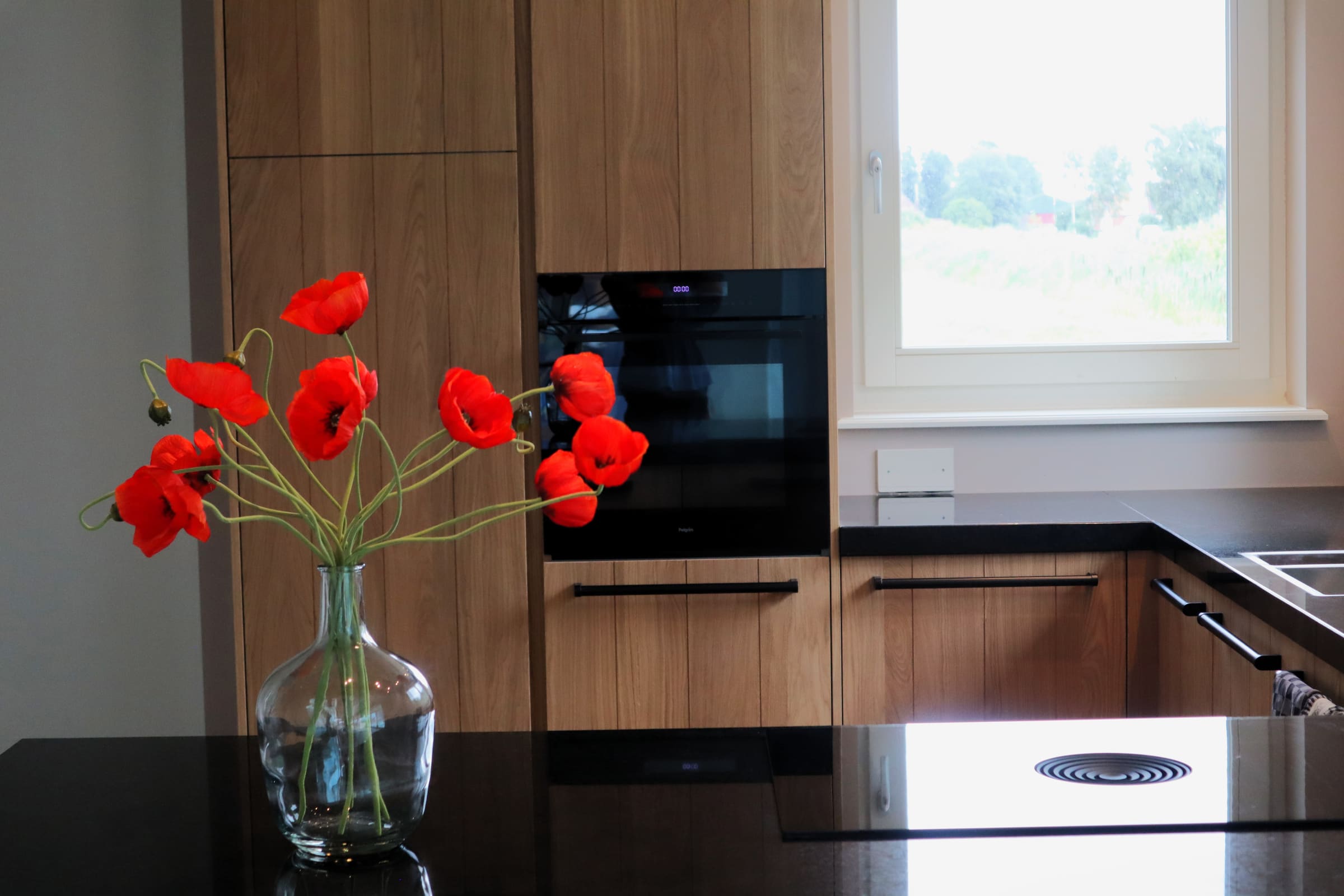 Klaprozen in een glazen vaas voor een houten keuken