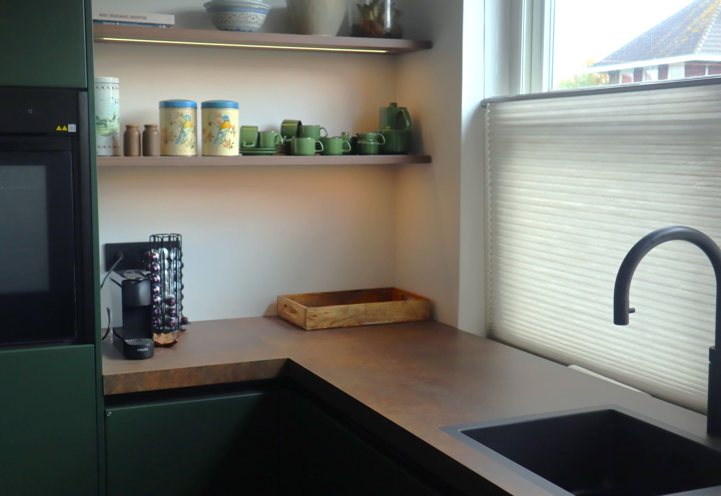 Groene keuken met open planken en een betonnen blad