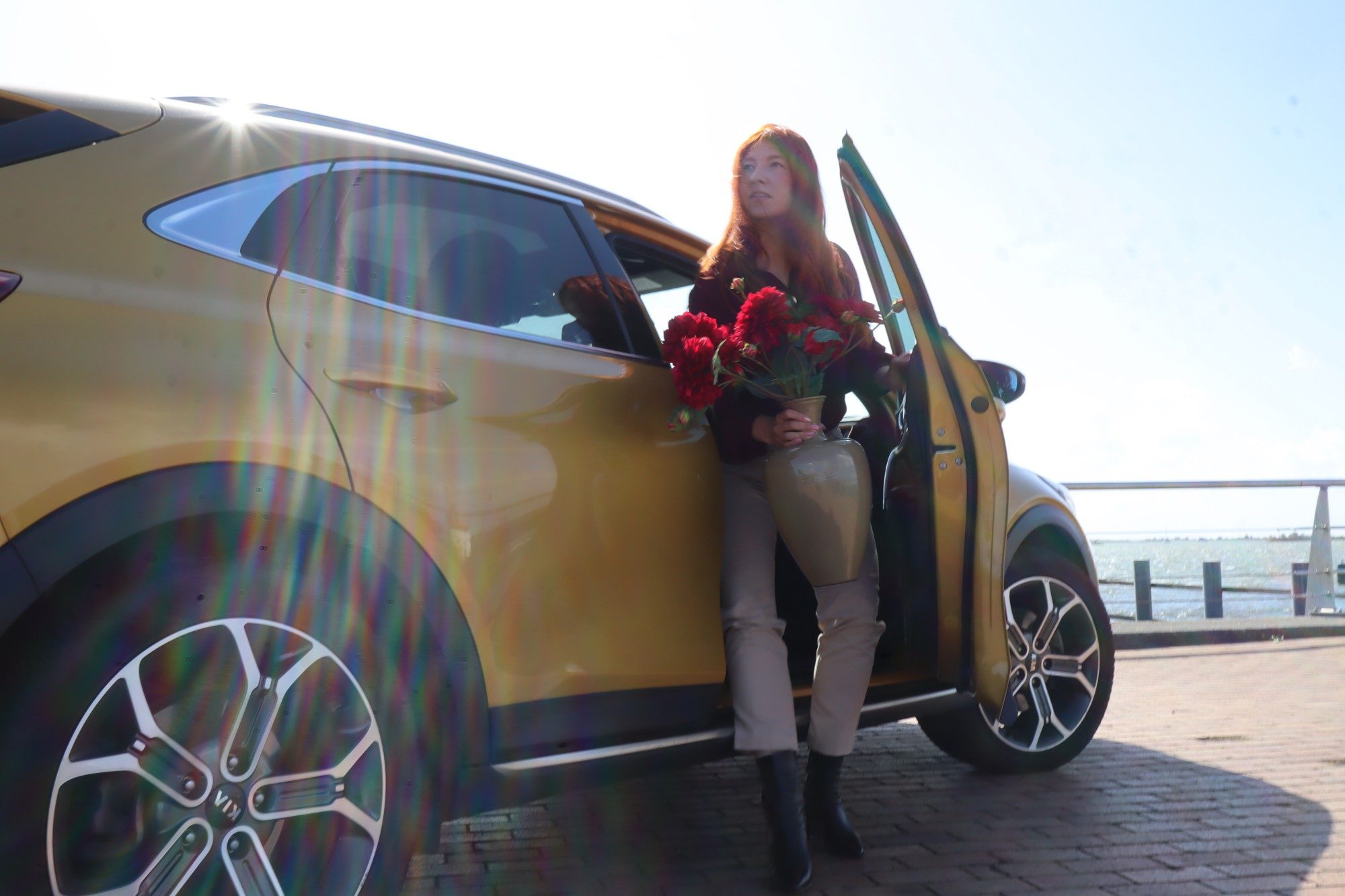 Leyla stapt met een boeket uit haar gele auto, onderweg naar een oplevering